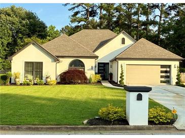 Charming single-story home with manicured lawn, lush landscaping, and an attached two-car garage at 2610 Stokesley Way, Snellville, GA 30078