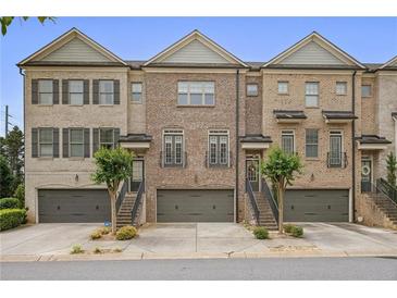 Beautiful townhome exterior featuring brick facade, two-car garage, and well maintained front yard at 1582 Cambridge Pl, Marietta, GA 30062