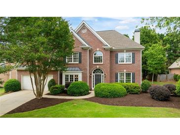 Charming two-story brick home with a manicured lawn, lush landscaping and an attached two car garage at 6695 Buckingham Cir, Cumming, GA 30040