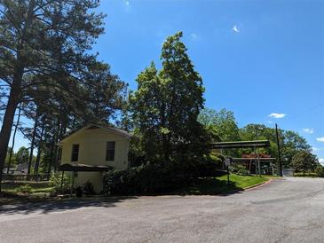 The exterior of this charming building is surrounded by lush greenery and mature trees on a sunny day at 395 Russell Sw Dr, Smyrna, GA 30082