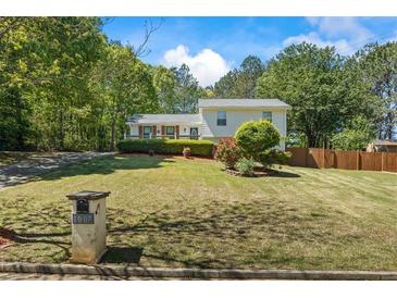 Charming two-story home featuring lush landscaping and a well-manicured lawn with mature trees at 1007 Wayne Dr, Snellville, GA 30078