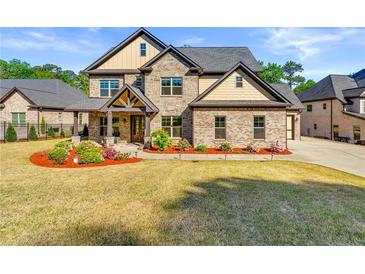 Beautiful two-story brick home featuring manicured lawn and inviting front porch with stone and cedar accents at 704 Rock Springs Rd, Lawrenceville, GA 30043