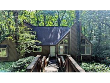 Charming home exterior with a wooden bridge leading to the front door, surrounded by lush greenery and mature trees at 3246 Able Ct, Marietta, GA 30062