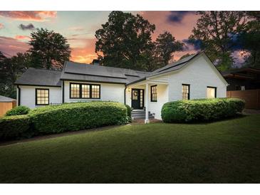 Charming painted brick home with black trim, dark roof, landscaped yard, and solar panels at 3734 Powers Ferry Nw Rd, Atlanta, GA 30342