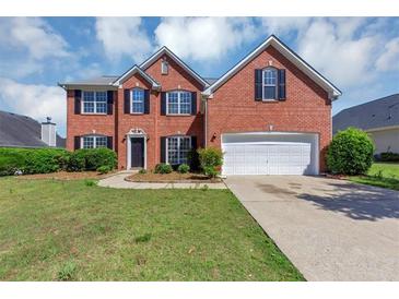 Charming two-story red brick home features a manicured lawn and a two-car garage at 1685 Great Oaks Dr, Lawrenceville, GA 30045