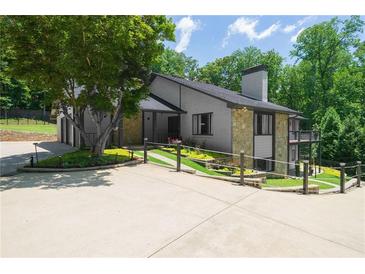Stylish home exterior with gray brick, stone accents, and a spacious driveway surrounded by manicured landscaping at 9701 Buice Rd, Alpharetta, GA 30022