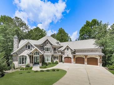 Stunning stone home with well-manicured lawn, three-car garage and impeccable curb appeal at 5039 Towne Lake Hills North, Woodstock, GA 30189