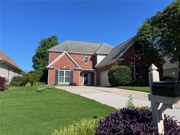 Charming brick home featuring a well-manicured lawn, attached garage, and classic architectural details at 5365 Glenhaven Dr, Cumming, GA 30041