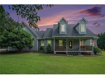 Charming two-story home with a welcoming front porch and lush green lawn at sunset at 225 W Union Grove Cir, Auburn, GA 30011
