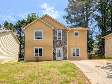 Two-story home featuring a stone facade, yellow siding, a green lawn and a concrete driveway at 2918 Pavia Circle, Austell, GA 30106
