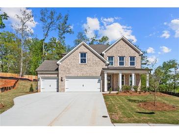 Stunning two-story brick home featuring a three-car garage, manicured lawn, and classic architectural details at 910 Melody Ridge Ln, Buford, GA 30518