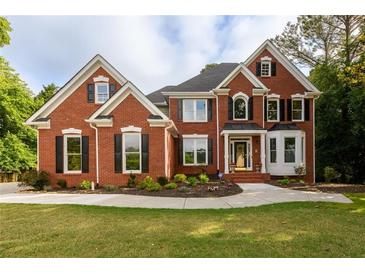 Stunning two-story red brick home featuring manicured lawn and lush landscaping at 620 Reeves Hill Pt, Lawrenceville, GA 30043