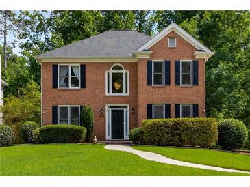 Charming two-story brick home with manicured lawn and mature trees, complete with black shutters and a classic front door at 1019 Legacy Walk, Woodstock, GA 30189