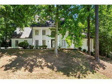 Stunning home featuring a white stucco exterior, black-framed windows and lush landscaping at 410 Glenmont Ct, Atlanta, GA 30350