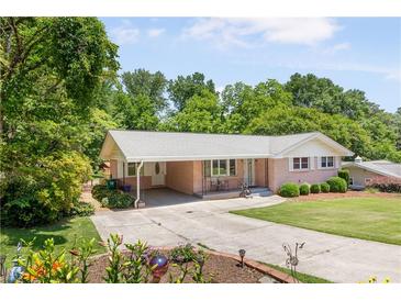 Charming brick home featuring a covered parking area, landscaped front yard, and mature trees at 701 Rosedale Se Dr, Smyrna, GA 30082