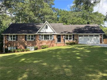 Charming brick home featuring a well-manicured lawn, a two-car garage, and traditional black window shutters at 1702 Montcliff Ct, Decatur, GA 30033