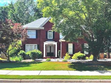 Charming two-story brick home featuring lush landscaping, a manicured lawn, and a welcoming front entrance at 2674 Misty Rock Cv, Dacula, GA 30019