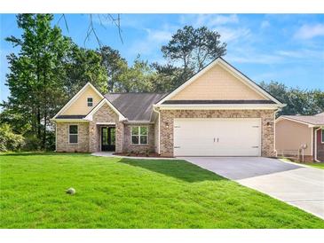 Charming brick home with a well-manicured lawn, attached garage, and welcoming entryway at 8544 Plumtree Dr, Riverdale, GA 30274
