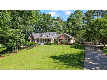 Charming brick home with manicured lawn, mature trees, and inviting front porch at 7376 Bates Dr, Cumming, GA 30040