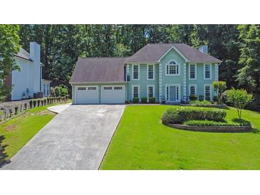 Attractive two-story home with a three-car garage and a well-maintained lawn, surrounded by mature trees at 985 Laurel Springs Ln, Marietta, GA 30064