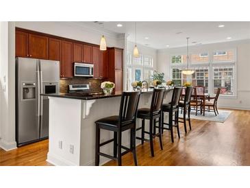 Modern kitchen with stainless steel appliances, breakfast bar and hardwood floors leading to the dining room at 1258 Dekalb Ne Ave # 112, Atlanta, GA 30307