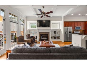 Bright living room featuring a fireplace, built-in shelving, ceiling fan and access to a balcony at 1258 Dekalb Ne Ave # 112, Atlanta, GA 30307