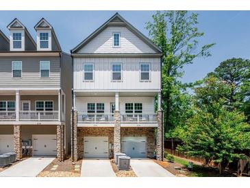 Charming townhouse with white siding, stone accents, and a welcoming covered porch perfect for enjoying the outdoors at 2106 Remy Ct, Kennesaw, GA 30144