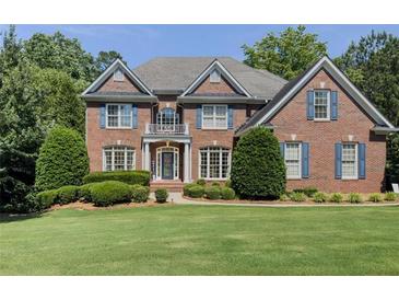Two-story red brick home featuring a well-manicured lawn and lush, mature landscaping at 1320 Kildare Ct, Snellville, GA 30078