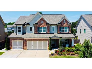 Inviting two-story home with a brick facade, three-car garage, landscaped front yard and charming curb appeal at 724 Laura Jean Ct, Buford, GA 30518