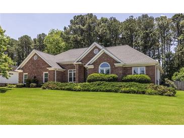 Beautiful brick home featuring lush landscaping, a manicured lawn, and a classic architectural design at 3845 Glen Ian Dr, Loganville, GA 30052
