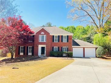 Charming two-story brick home with a well-maintained front yard and three-car garage at 415 Wood Trace Ct, Alpharetta, GA 30022