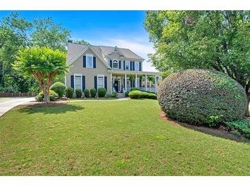 Charming two-story home featuring lush landscaping, a sprawling green lawn, and a welcoming front porch at 1274 Cotton Gin Dr, Powder Springs, GA 30127
