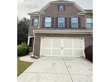 Two car garage with white doors and brown brick exterior at 5850 Shiloh Woods Dr, Cumming, GA 30040