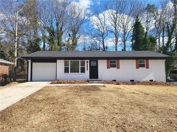 Charming single-story home with a white brick exterior, black roof, and attached garage at 4664 Ryan Rd, Conley, GA 30288