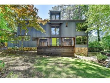 Stunning modern home with a wooden porch, stone accents, a green door, and surrounded by lush greenery at 945 Tiber Cir, Alpharetta, GA 30022