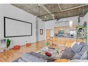 Modern loft with an open floor plan, hardwood floors, exposed ductwork, and a large projector screen at 3235 Roswell Ne Rd # 702, Atlanta, GA 30305