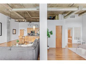 Bright open-concept living room featuring exposed pipes, hardwood floors, and sight lines into the kitchen and bathroom at 3235 Roswell Ne Rd # 702, Atlanta, GA 30305