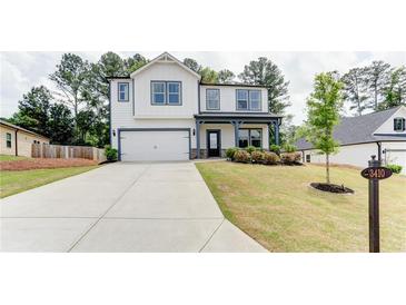 Charming two-story home featuring a spacious driveway, landscaped yard, and modern architectural details at 3410 Summerpoint Xing, Cumming, GA 30028