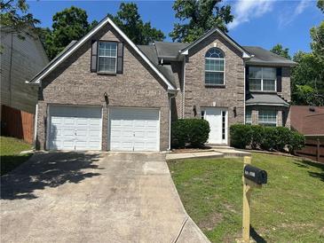 Charming brick home featuring a two-car garage, landscaped yard, and classic architectural details at 3827 Micah Ln, Ellenwood, GA 30294