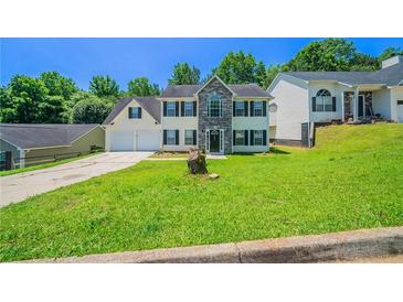 Traditional two-story home with stone accents, a well-manicured lawn, and an attached two-car garage at 3283 Sugar Creek Falls Se Ave, Atlanta, GA 30316