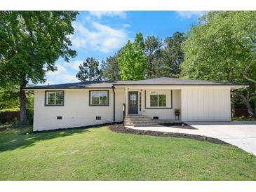 Charming home with white painted brick, dark trim, fresh landscaping, and a well-manicured lawn at 6090 Heritage Se Way, Mableton, GA 30126