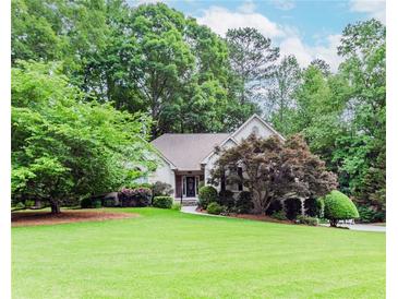 Landscaped home exterior boasting a well-manicured lawn, mature trees, and a charming front entrance at 1205 Rivershyre Ne Pkwy, Lawrenceville, GA 30043