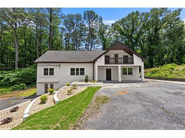 Charming two-story white home with a balcony, lovely landscaping, and a spacious driveway surrounded by mature trees at 1887 Shalimar Dr, Atlanta, GA 30345