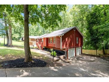 Inviting red home with a two-car garage and a lovely green yard surrounded by mature trees offering plenty of shade at 4771 N Springs Nw Rd, Kennesaw, GA 30144