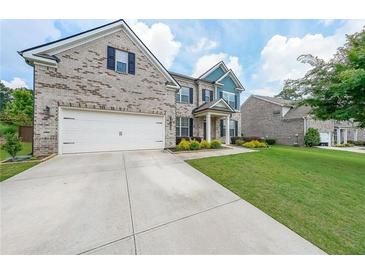 Charming brick home featuring a two-car garage and a well-manicured front lawn at 5789 Creek Indian Dr, Sugar Hill, GA 30518
