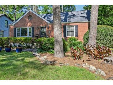 Charming brick home featuring a well-manicured front yard with mature trees and lush landscaping at 1521 Deerwood Dr, Decatur, GA 30030