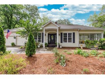 Charming single-story home with a welcoming front porch, lush landscaping, and an American flag at 791 E Main Street, Canton, GA 30114