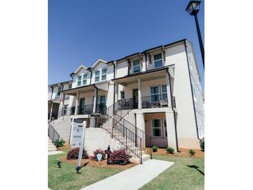 Charming white brick townhome featuring multiple levels, inviting staircases, and manicured landscaping at 3564 Shore Wood Ave, Lawrenceville, GA 30044