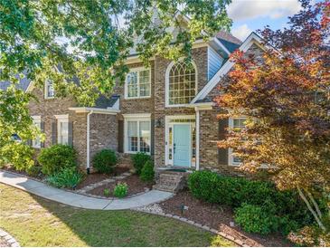 Charming brick home with a manicured front yard, beautiful landscaping and a light blue front door at 4295 Cami Way, Buford, GA 30519