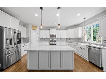 Bright kitchen features stainless steel appliances, granite counters, recessed lighting, and hardwood floors at 4295 Cami Way, Buford, GA 30519